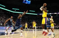 LeBron James (Lakers) arremessa a bola no ar, com um defensor do Minnesota Timberwolves estendendo o braço.