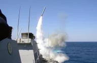Míssil é lançado de um navio de guerra no mar, com fumaça e água espirrando.